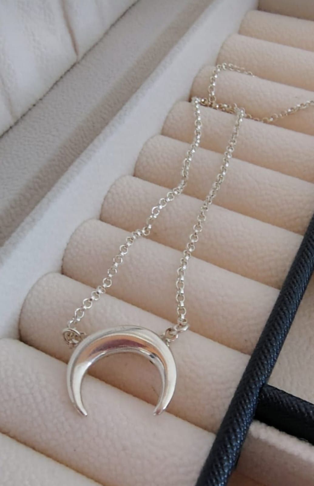 Collar con colgante de luna creciente plateada en el cuello de una mujer, usado con una blusa blanca.