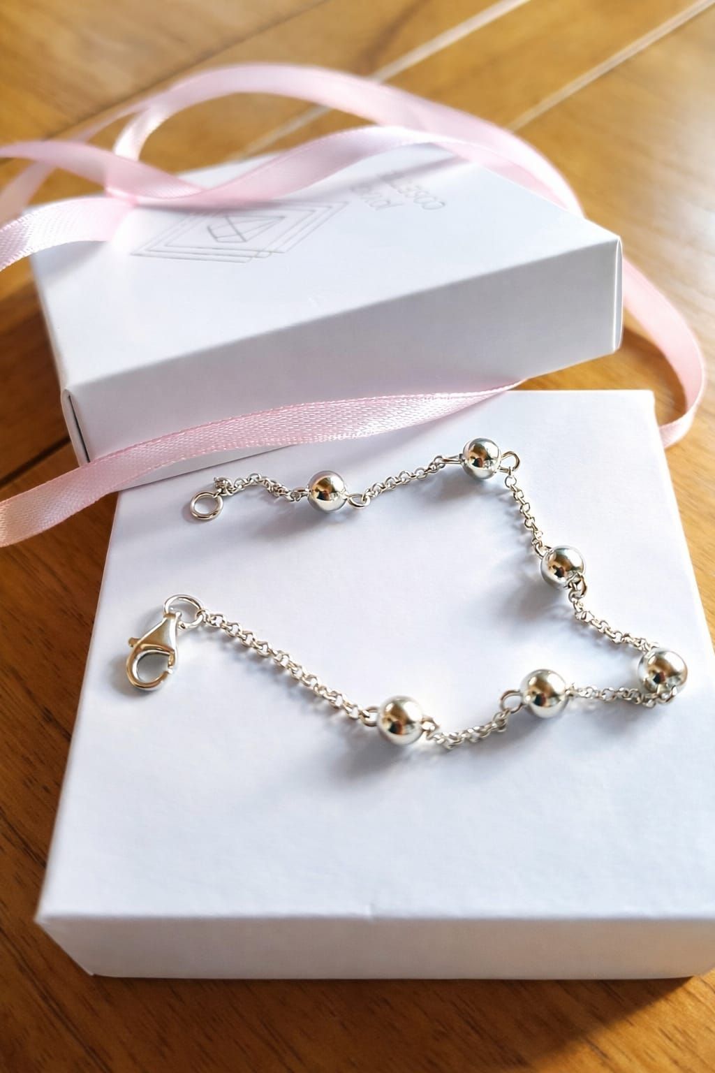 Pulsera de cuentas de plata en la muñeca con un dije colgante y una delicada cadena.
