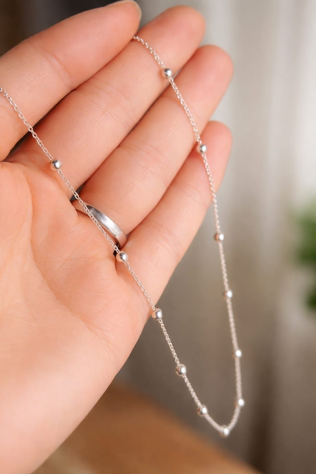 Primer plano de una mujer con un delicado collar de plata y una blusa blanca con escote en V.