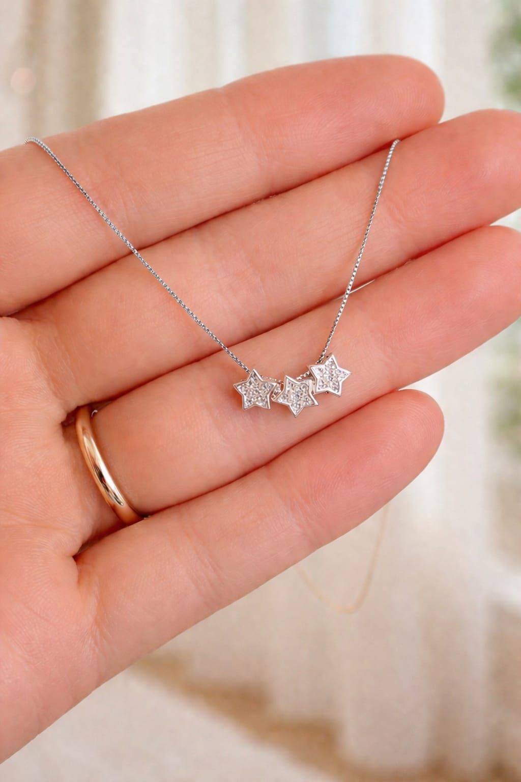 Collar de plata con un pequeño colgante sobre una blusa blanca con escote en V.
