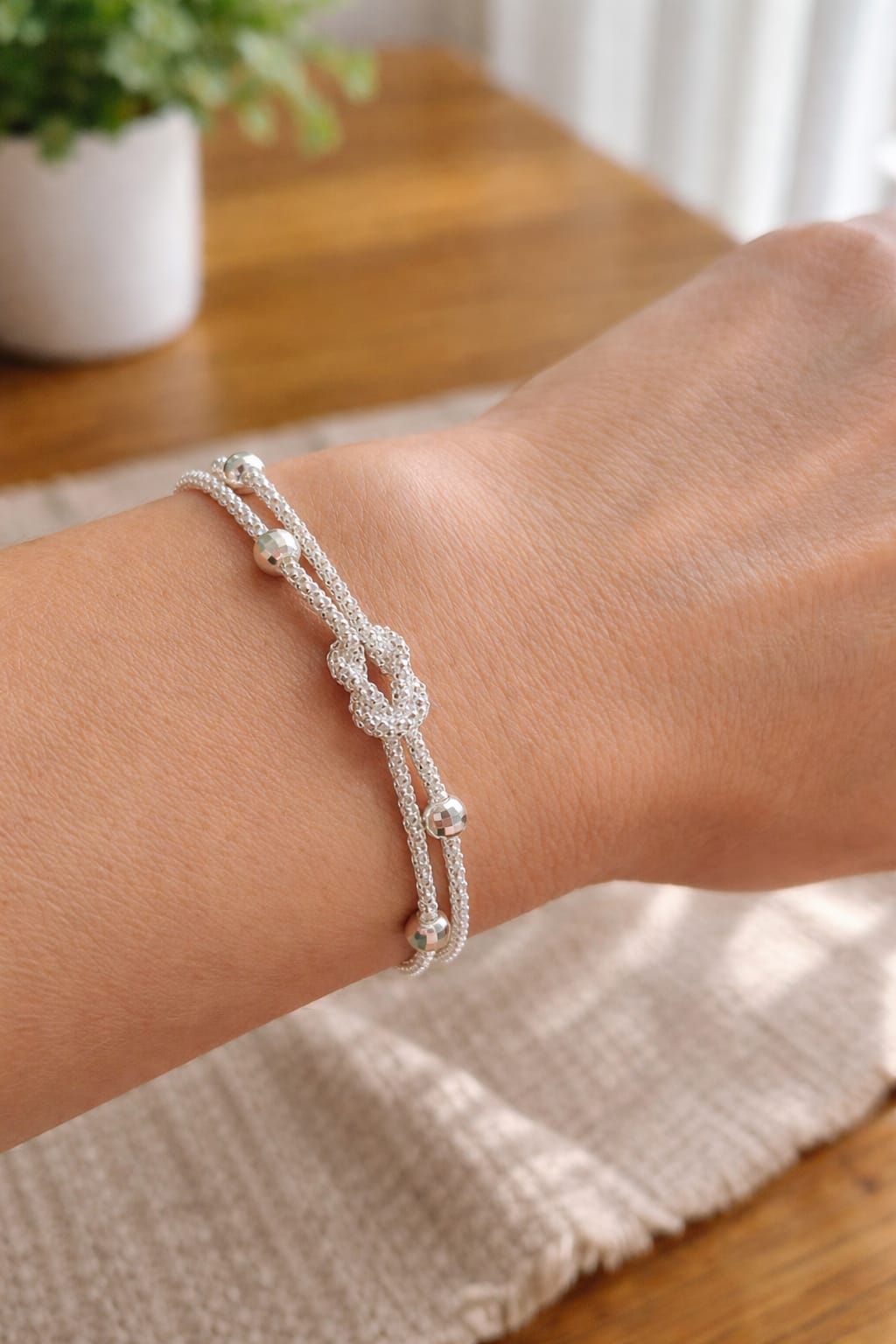 Pulsera de plata con cierre en forma de corazón que descansa sobre una palma abierta.
