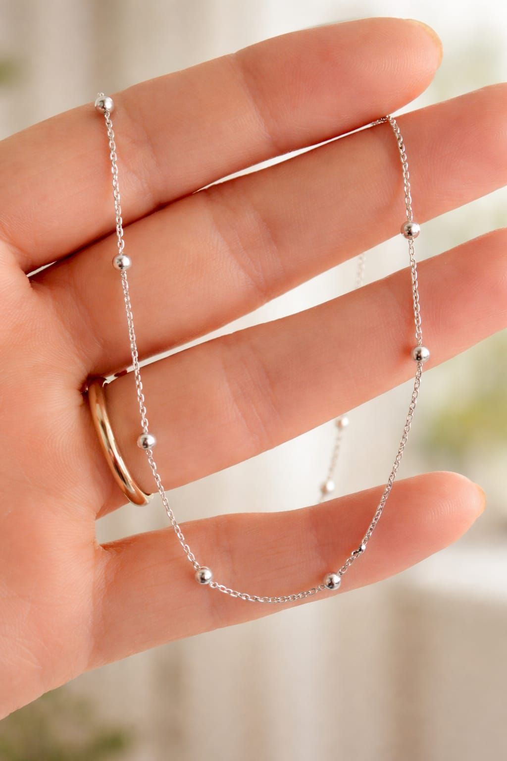 Collar de plata delicado en una persona que lleva una blusa rosa pálido con escote en V.
