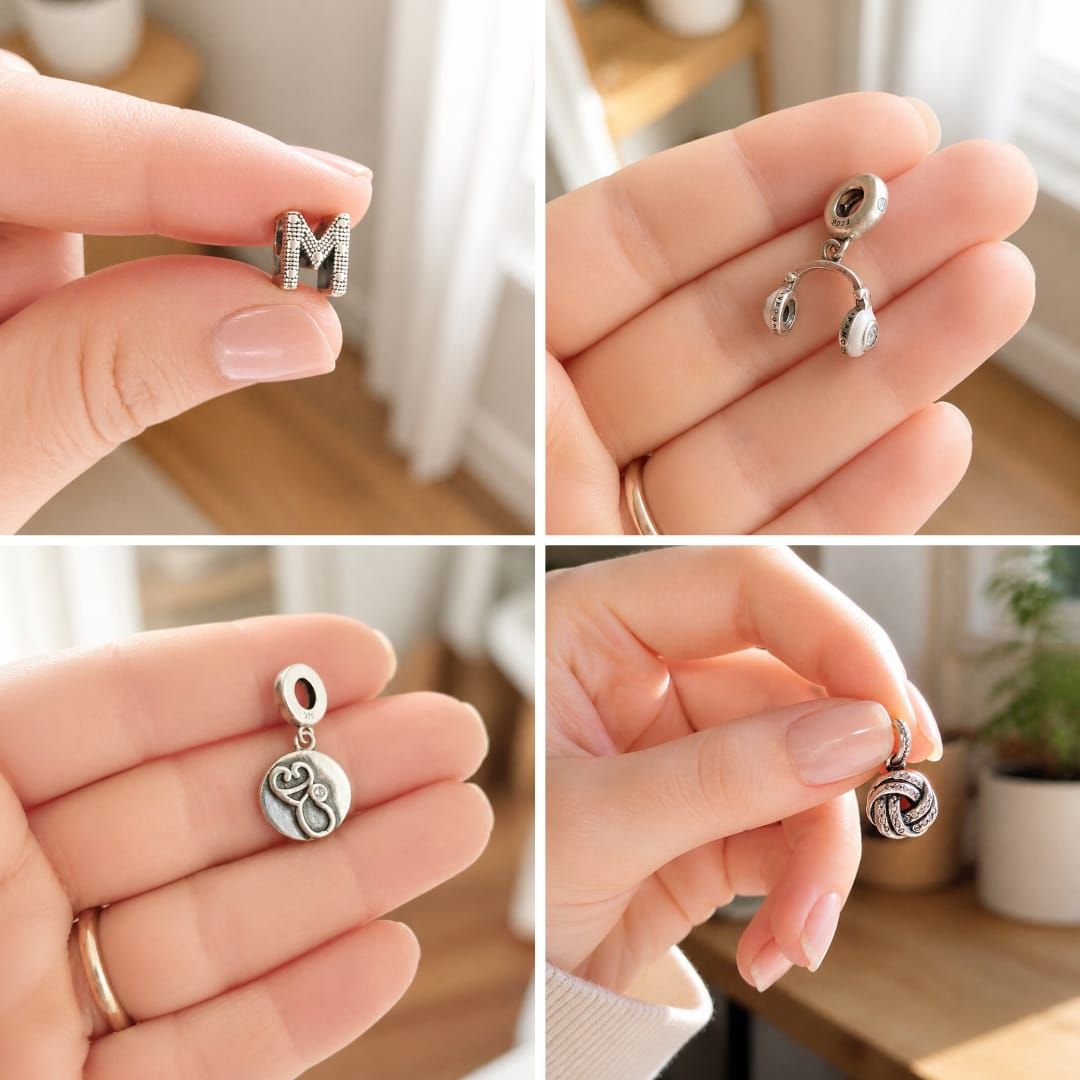 Manos sosteniendo cuatro pequeños pendientes colgantes de plata en un entorno interior luminoso.