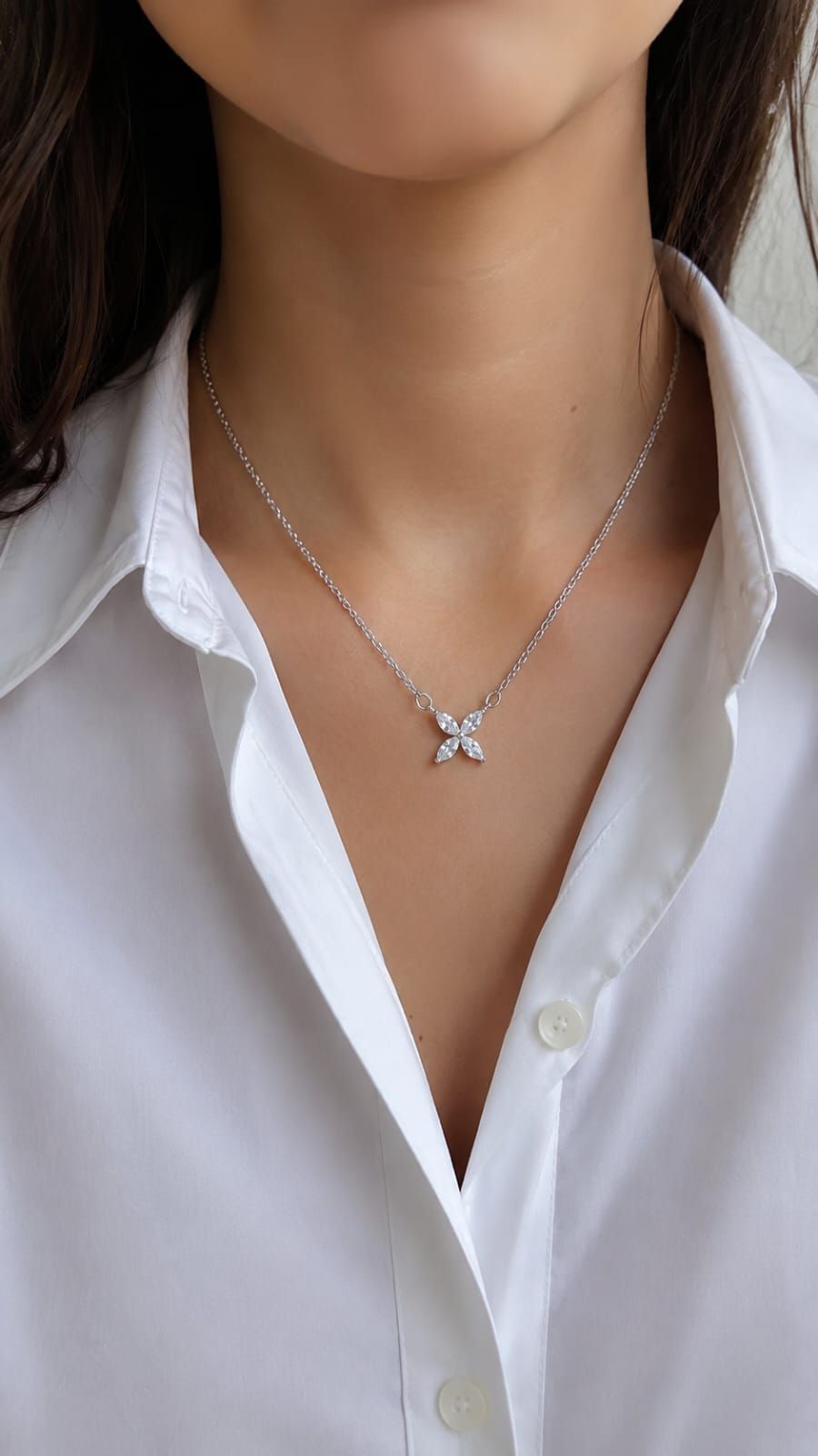 Primer plano de una camisa blanca y un collar con colgante de estrella plateada en el cuello de una persona.
