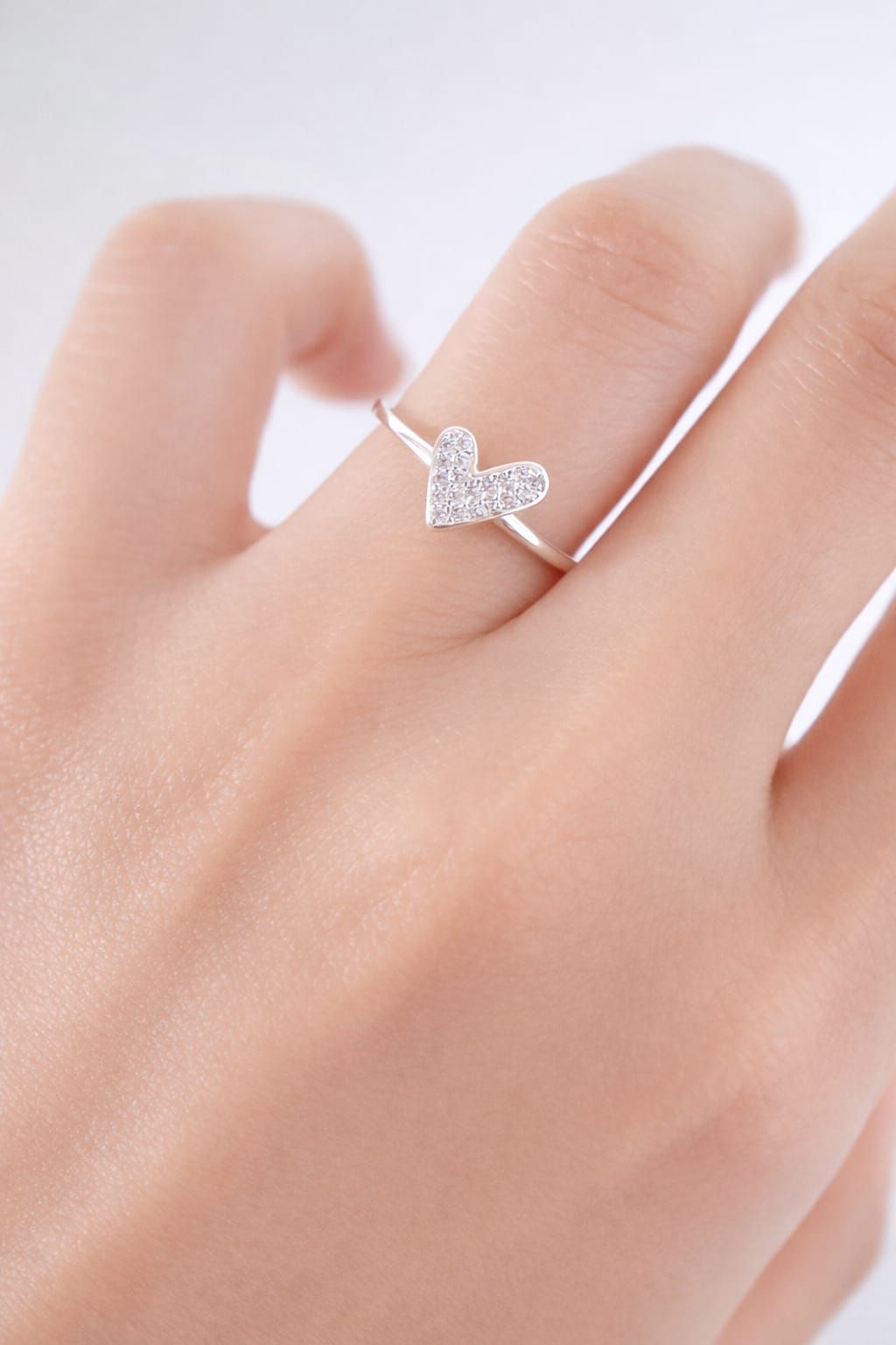 Mano con un anillo de mariposa de plata sobre un fondo rosa suave