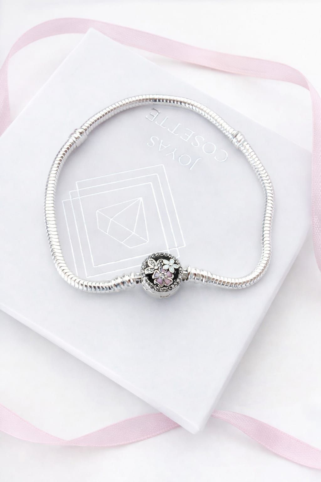 Primer plano de una mano que lleva una pulsera de plata con un colgante de cristal redondo.