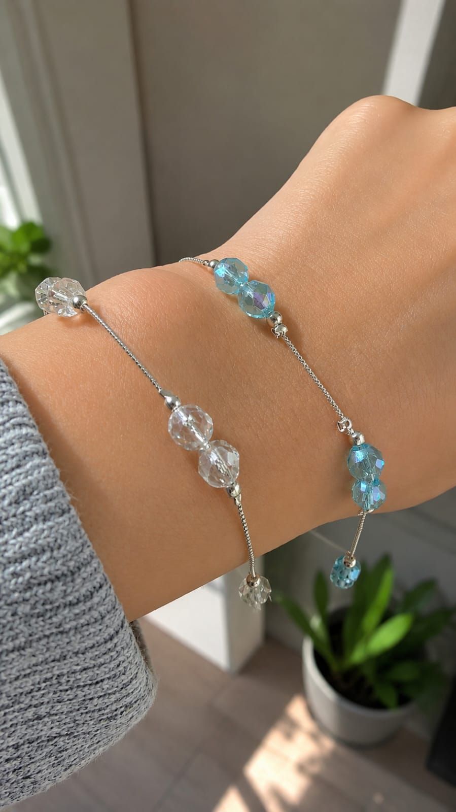Collar de cuentas azul claro y pendientes dorados expuestos en un joyero blanco con una planta al fondo.