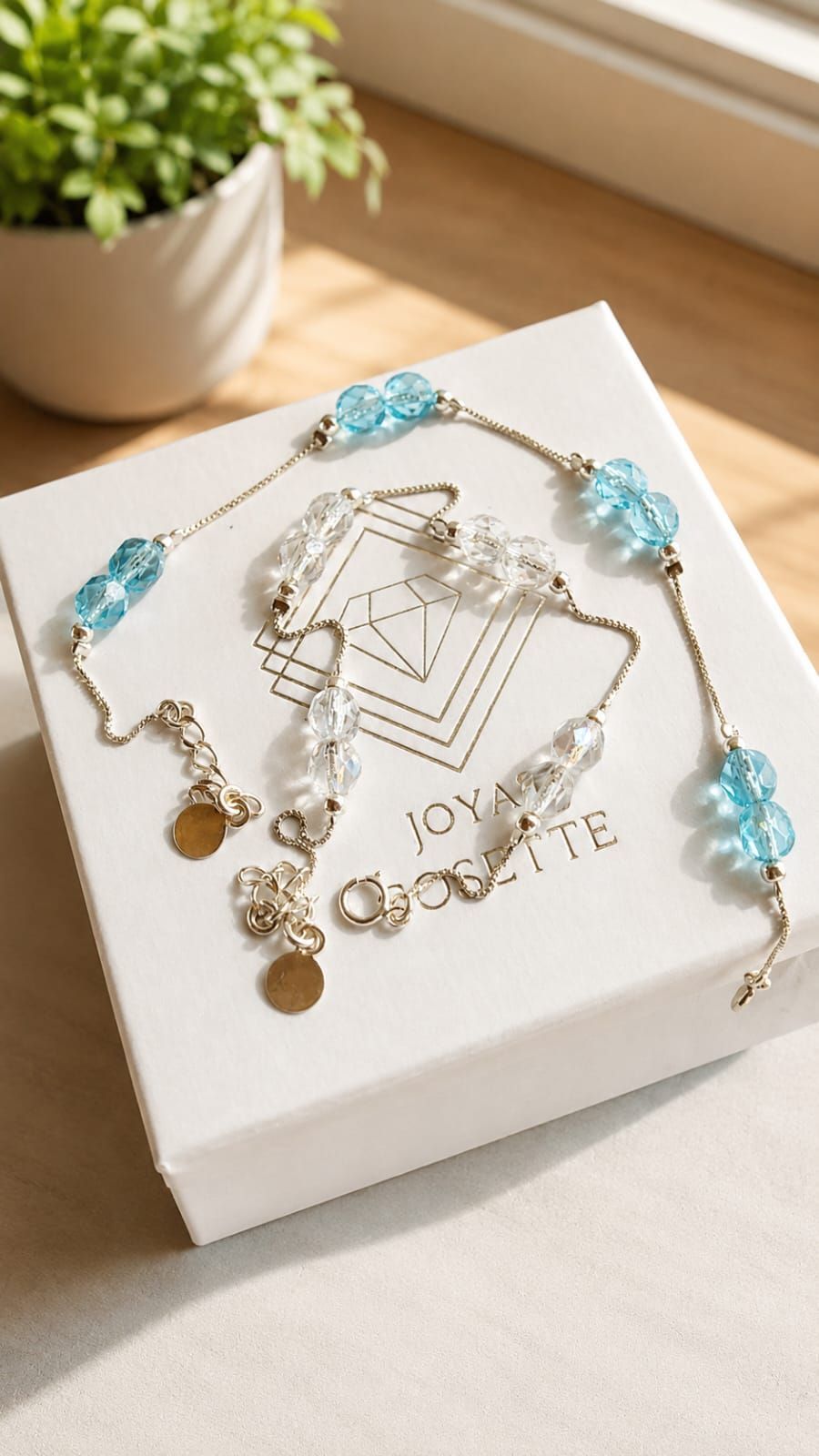 Collar de cuentas azul claro y pendientes dorados expuestos en un joyero blanco con una planta al fondo.