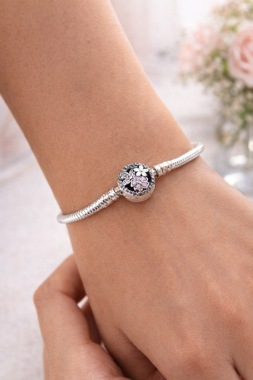 Primer plano de una mano que lleva una pulsera de plata con un colgante de cristal redondo.