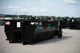 A large black dumpster with the letters etm on it