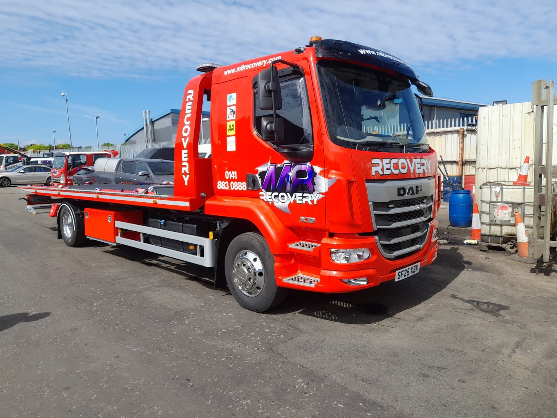 Red DAF recovery truck parked outside on a sunny day. 