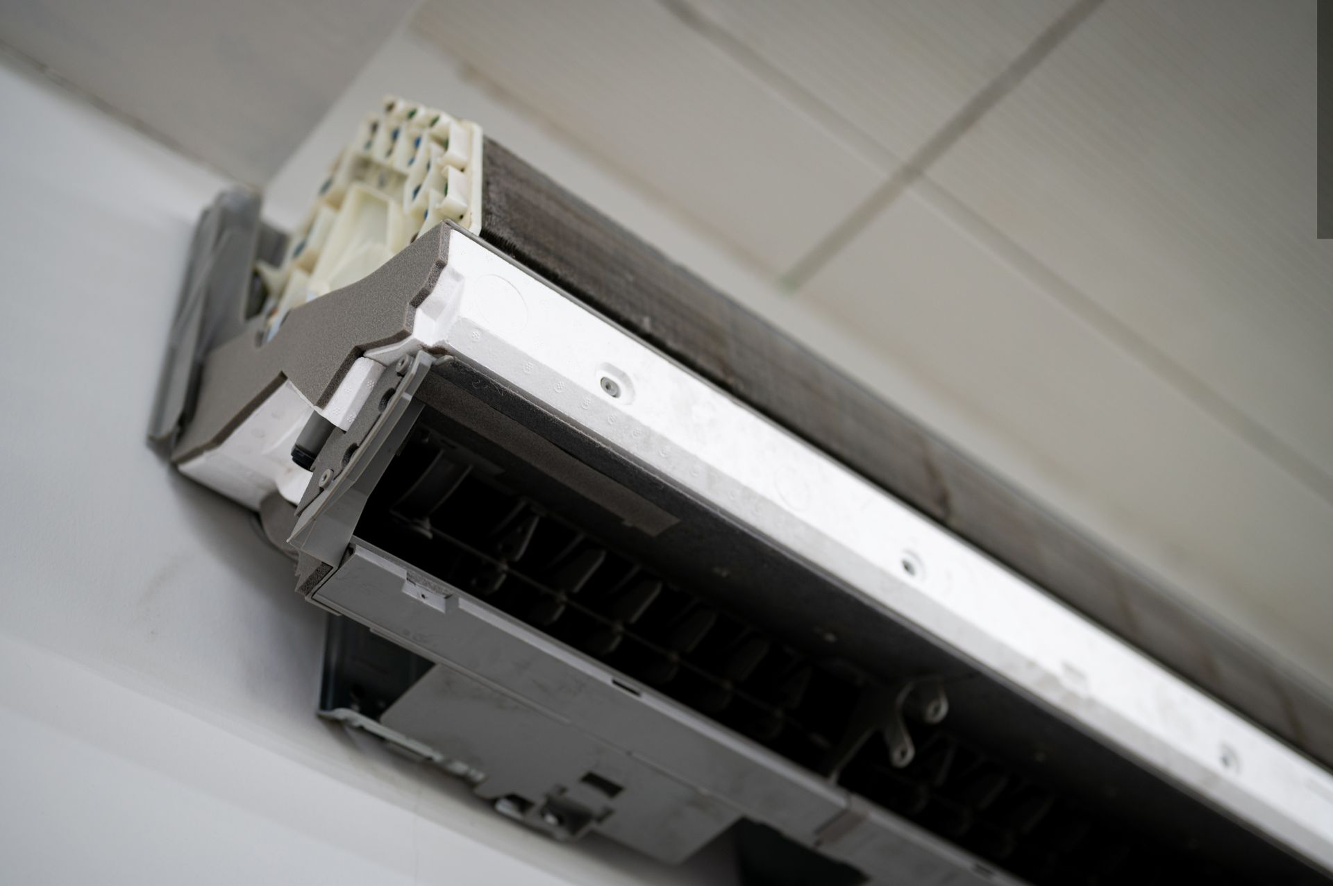 Open ceiling air conditioner unit with exposed vent and wiring
