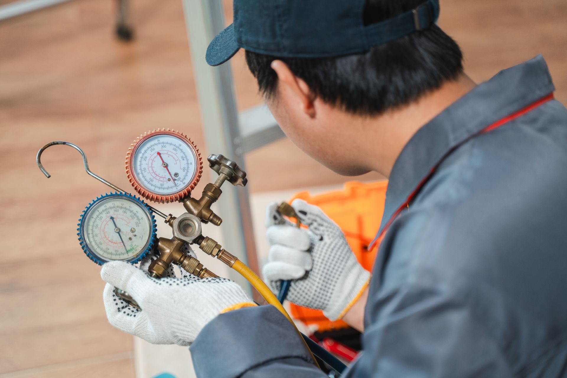 Technician using manifold gauges to service an air conditioner outdoors