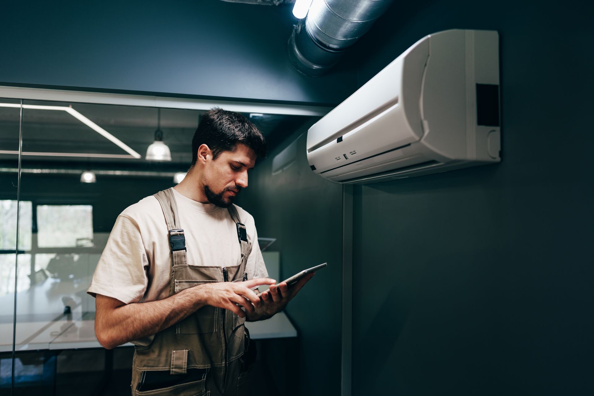 Technician checking an air conditioner unit in a workshop with a clipboard