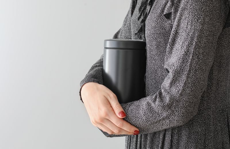 Person holding a black insulated tumbler against a gray background