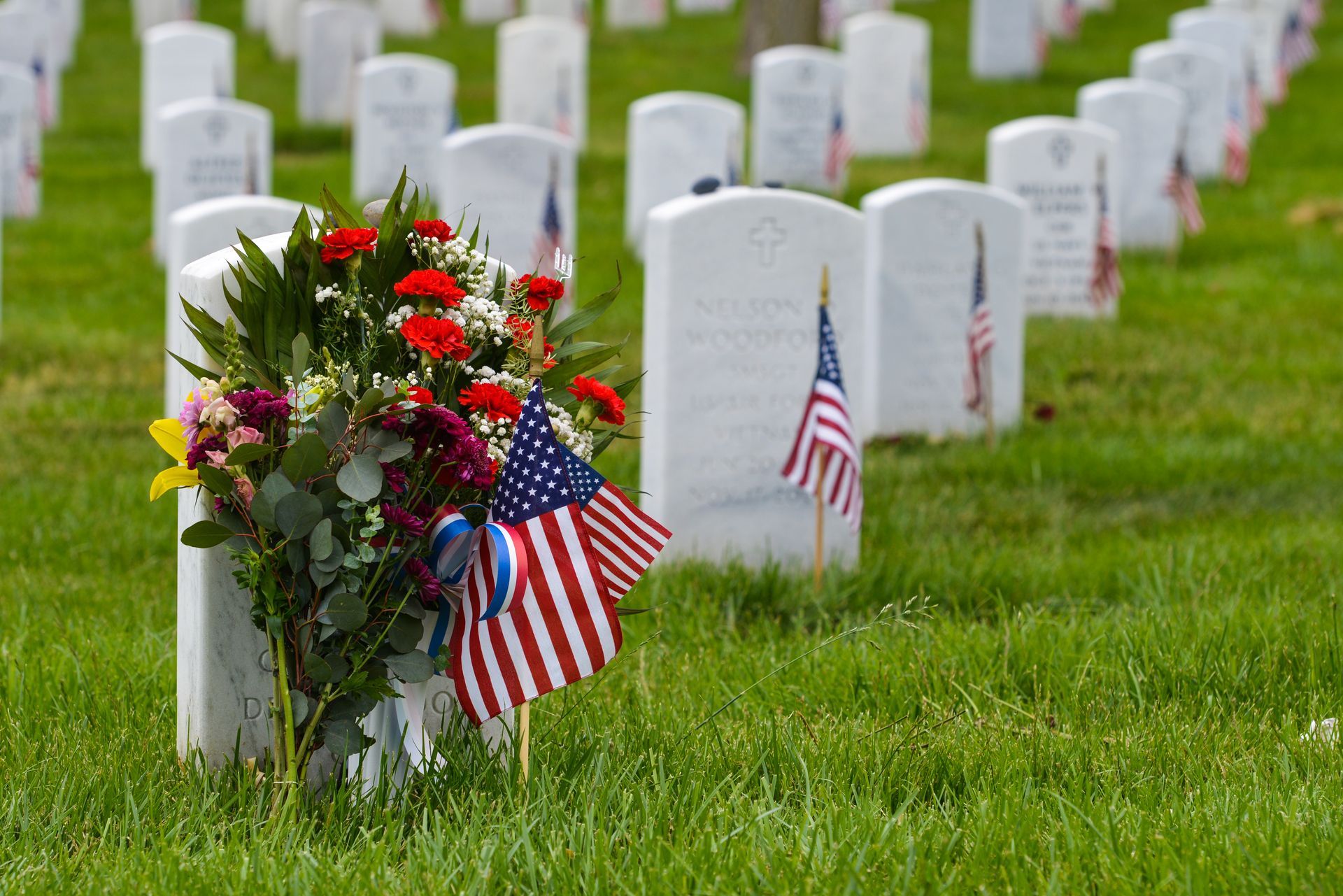 Military graves with flowers and American flags in a cemetery