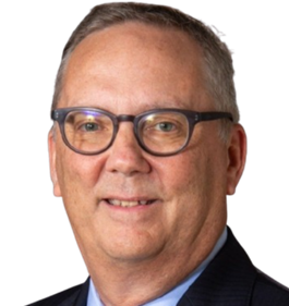 Headshot of a person wearing glasses and a dark suit with a light blue shirt, smiling against a white background.