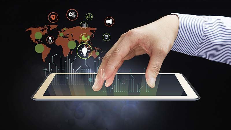 A man's hand resting above a tablet while a map of the world highlighting information projects from it