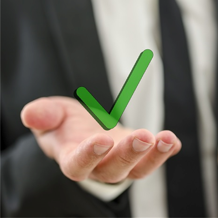A businessman's hand holding a green checkmark 