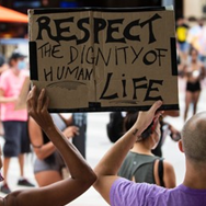 Hands holding a cardboard sign: