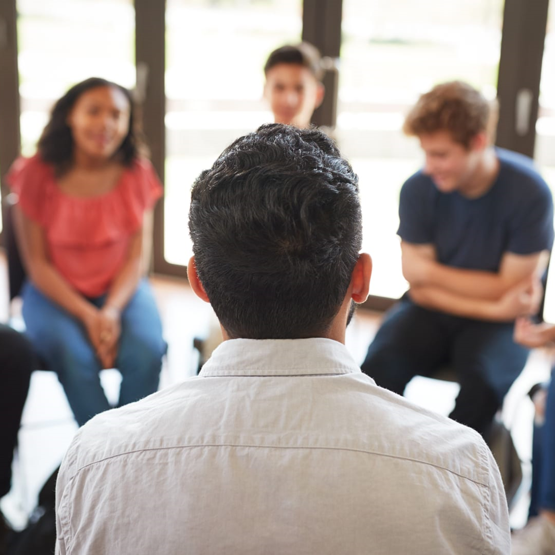A group of young pèople sitting in a circle talking to an interviewer 