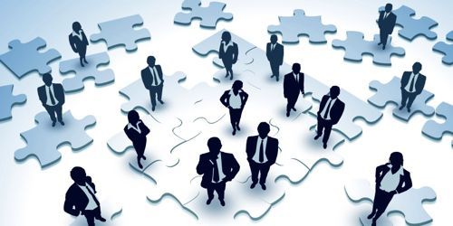 A group of business people in suits standing on top of puzzle pieces