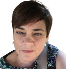 A person with short, dark hair and light eyes, wearing a patterned top and a necklace, looking towards the camera.