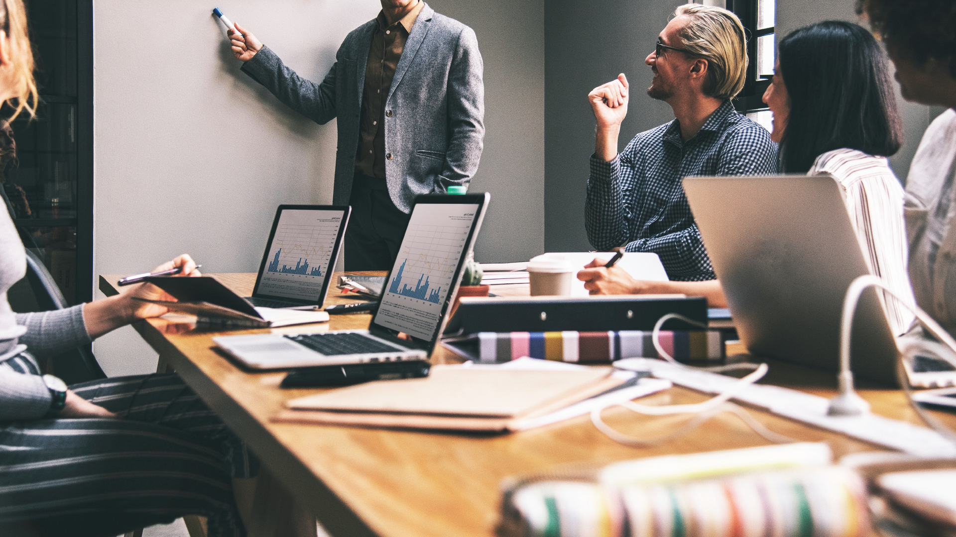 A diverse team attends a meeting in a conference room and presents data.
