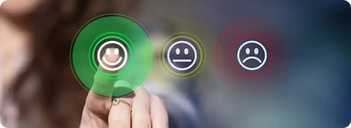Hand selecting a smiling face icon from three rating icons on a blurred background