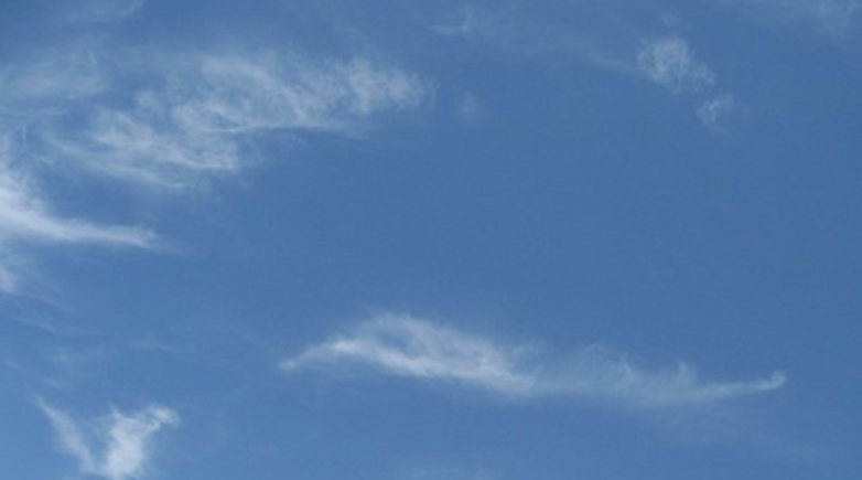 A bright blue sky with whisps of clouds
