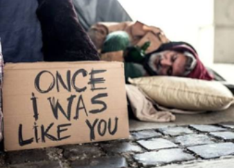 Protester sleeping beside sign reading “ONCE I WAS LIKE YOU” on a sidewalk.