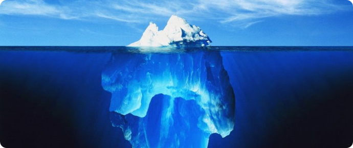 Iceberg floating in the ocean, with most of its blue mass submerged below the waterline.