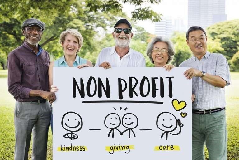 A diverse group of adults holding a sign depicting attributes of non-profits.