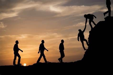 A group of people are helping each other climb a mountain.
