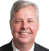 A man in a suit and tie is smiling for the camera