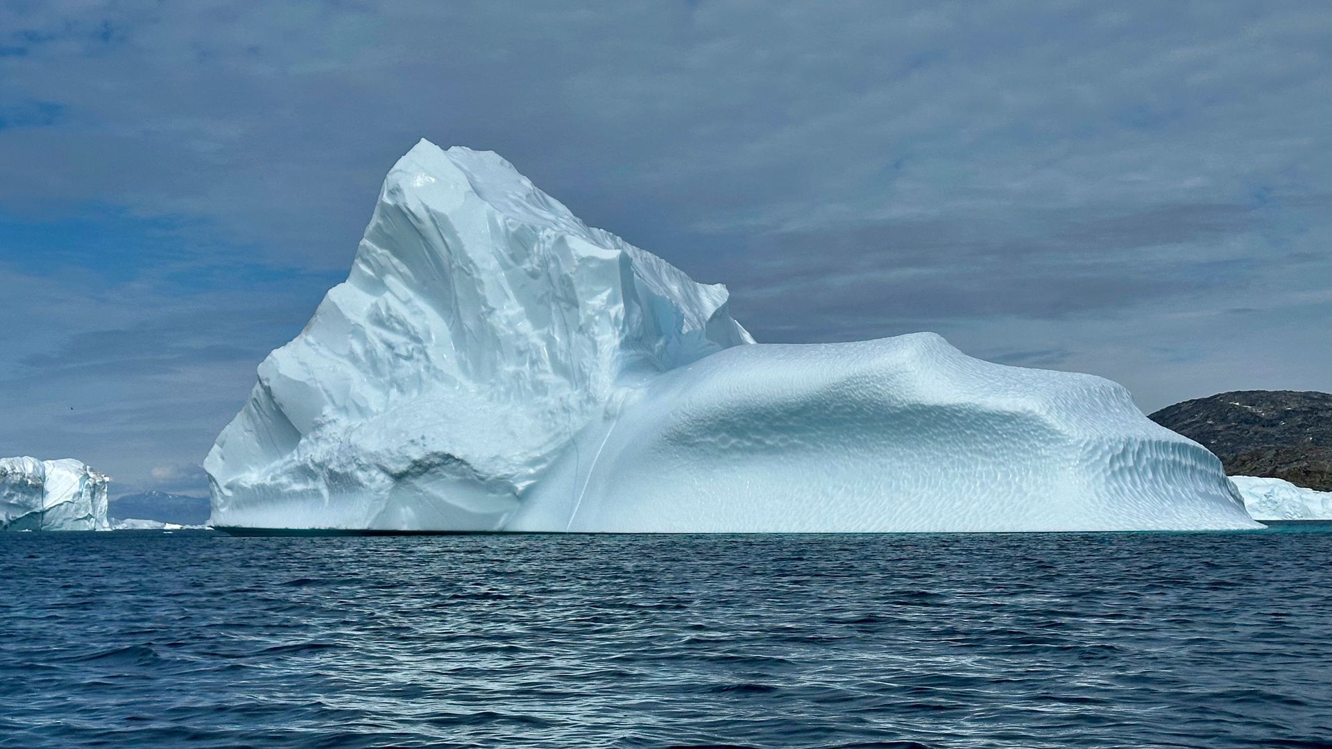 Iceberg floating in a deep blue ocean, with most of its mass hidden underwater.