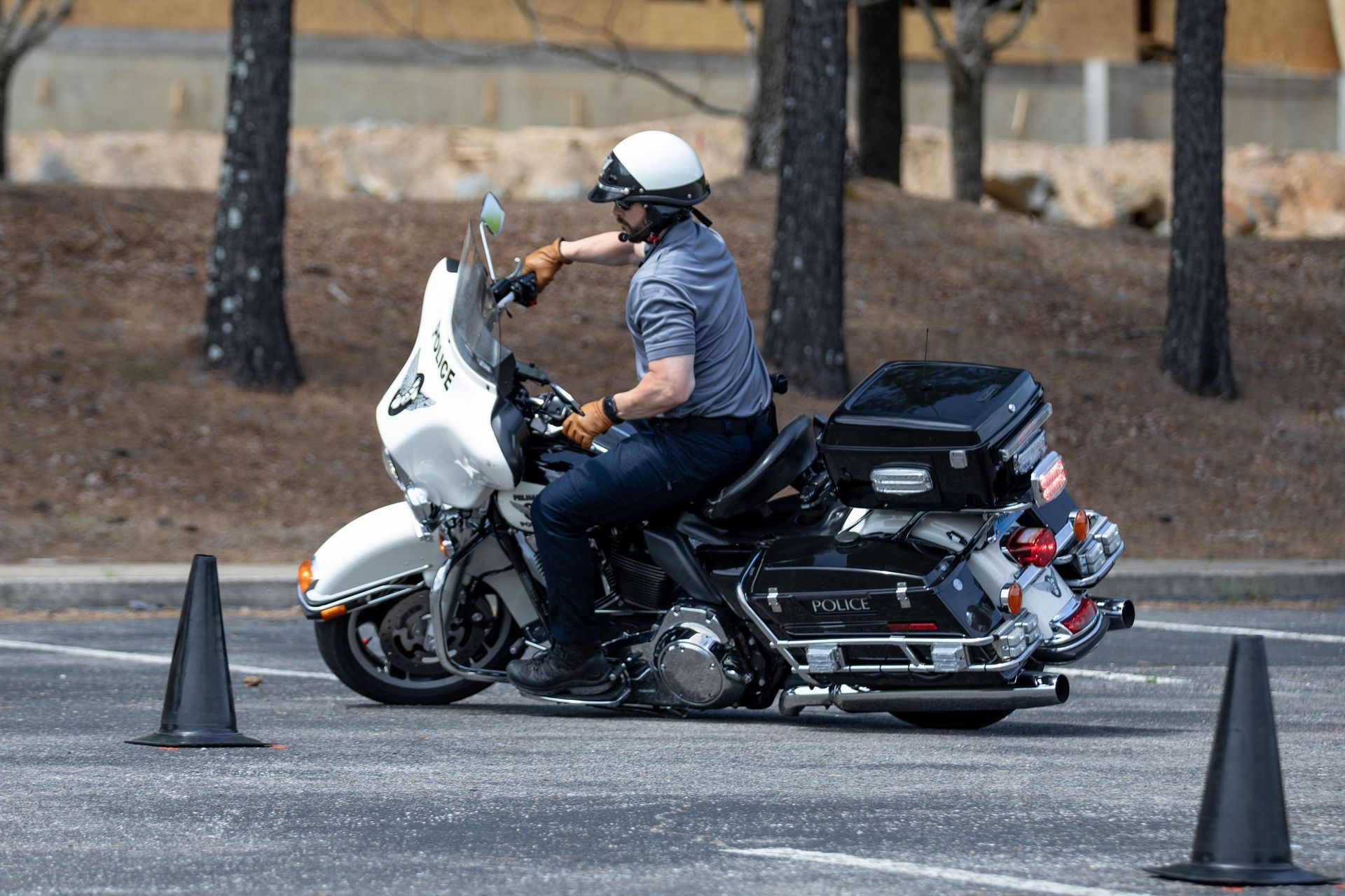 Motorcyclist on a white touring bike navigating a parking lot around traffic cones