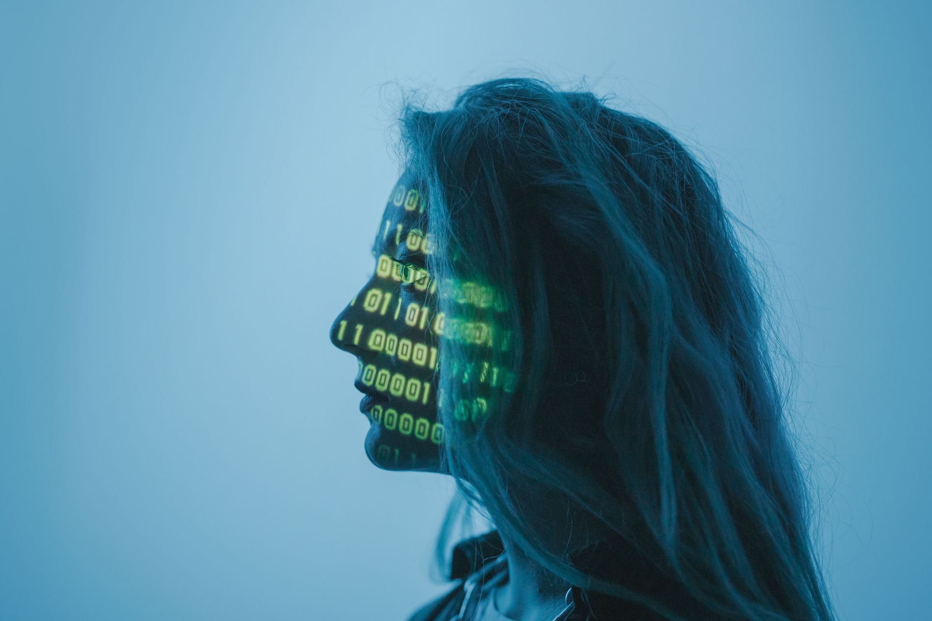 Profile silhouette with binary code projected on the face against a blue background