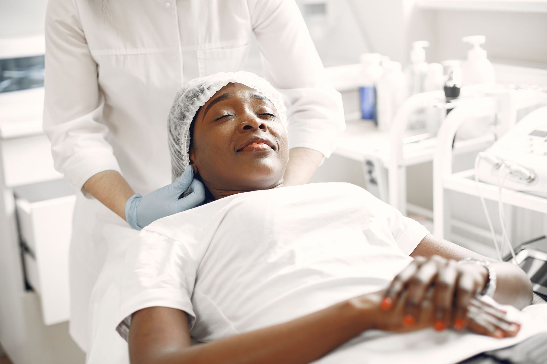 Patient reclining in a dental chair while a clinician examines their head with gloved hands