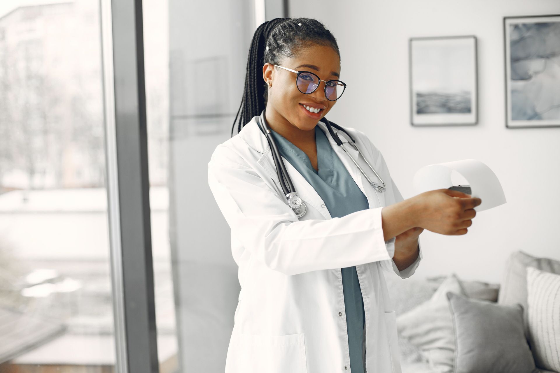 Doctor in a white coat holding and reading a document in a bright clinic room