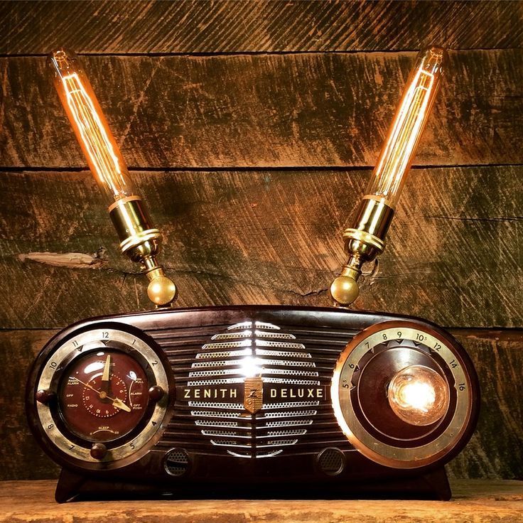 Vintage radio with glowing orange lights and two illuminated glass tubes on a wooden background