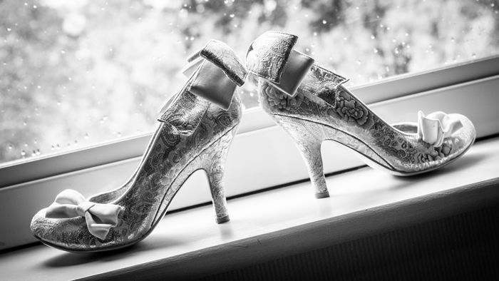 A pair of wedding shoes are sitting on a window sill.