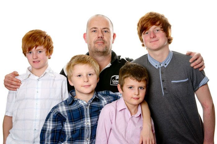 A group of young boys are posing for a picture with their father