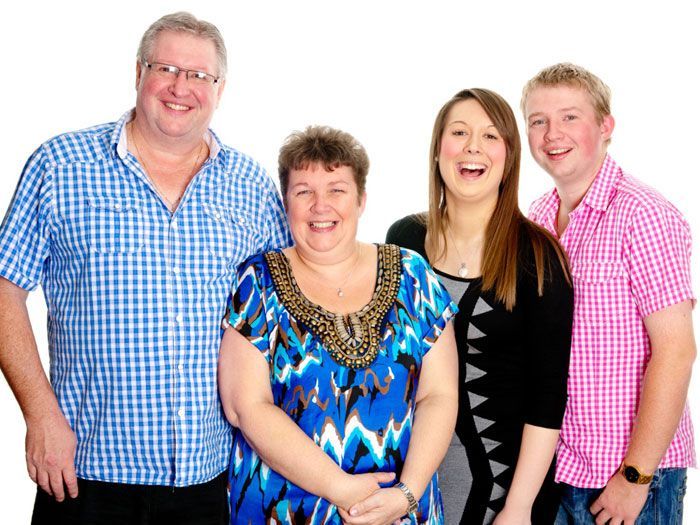 A family posing for a picture together and smiling for the camera