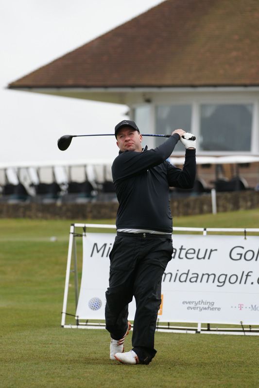 A man is swinging a golf club on a golf course