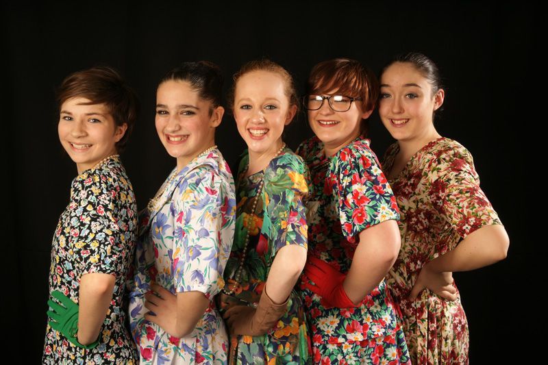 A group of young girls in floral dresses are posing for a picture.