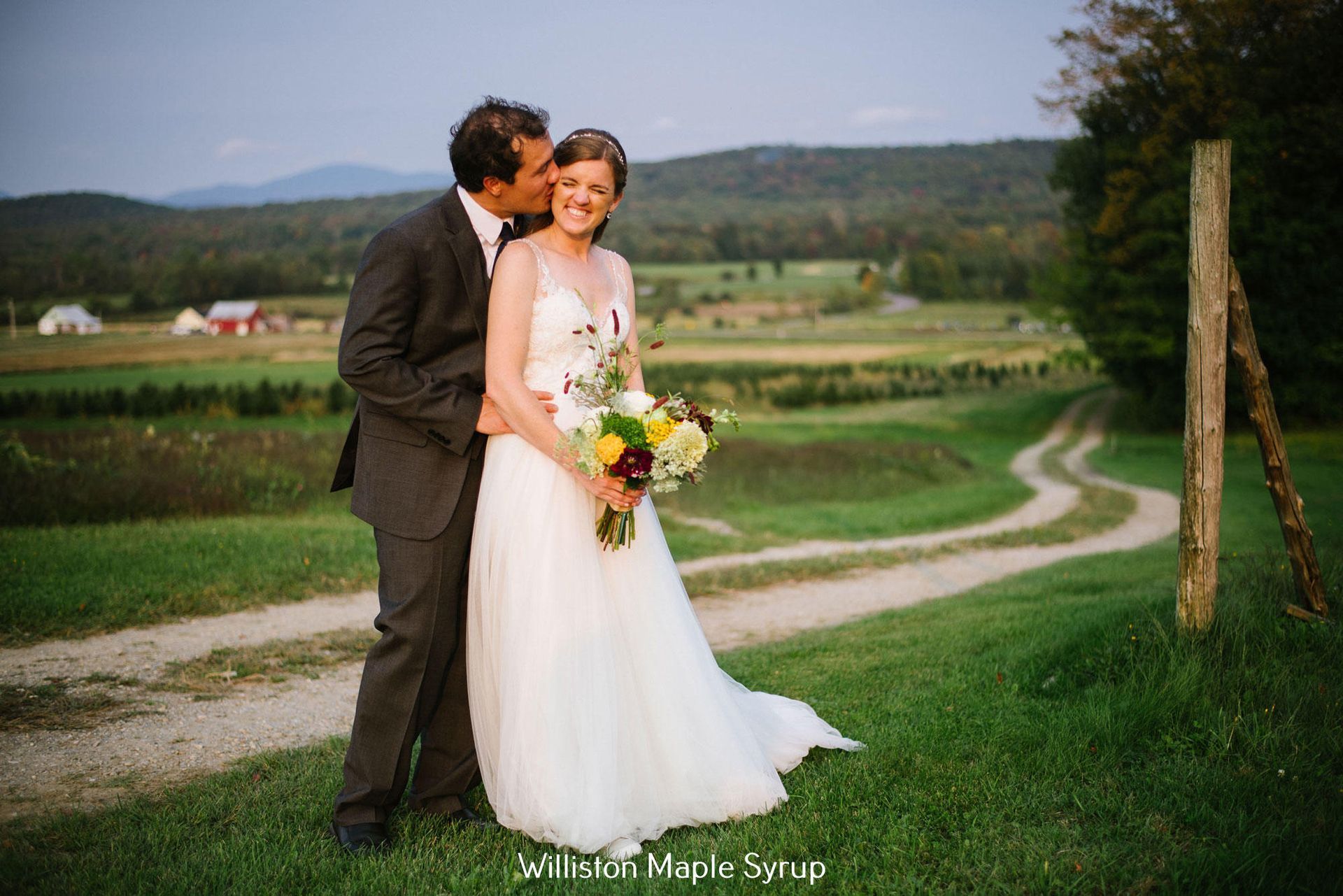 Bride and groom embrace on a scenic path at Isham Family Farm wedding venue.