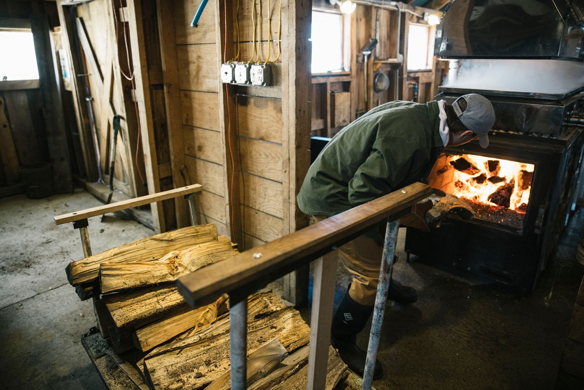 Isham family member stoking the fire for the maple boiling process in isham family farm maple shack