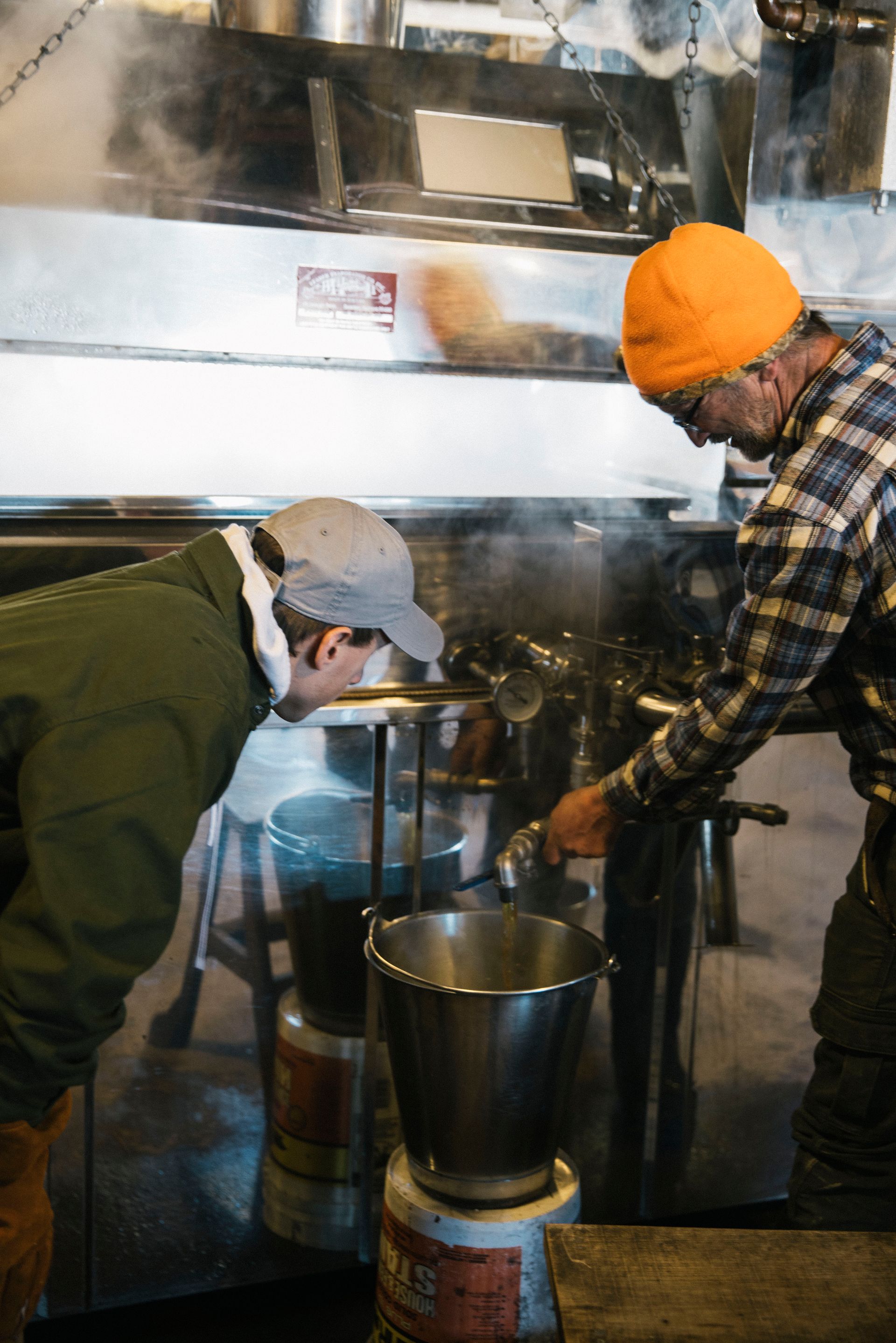 two members of the isham family inspecting the maple boiling process