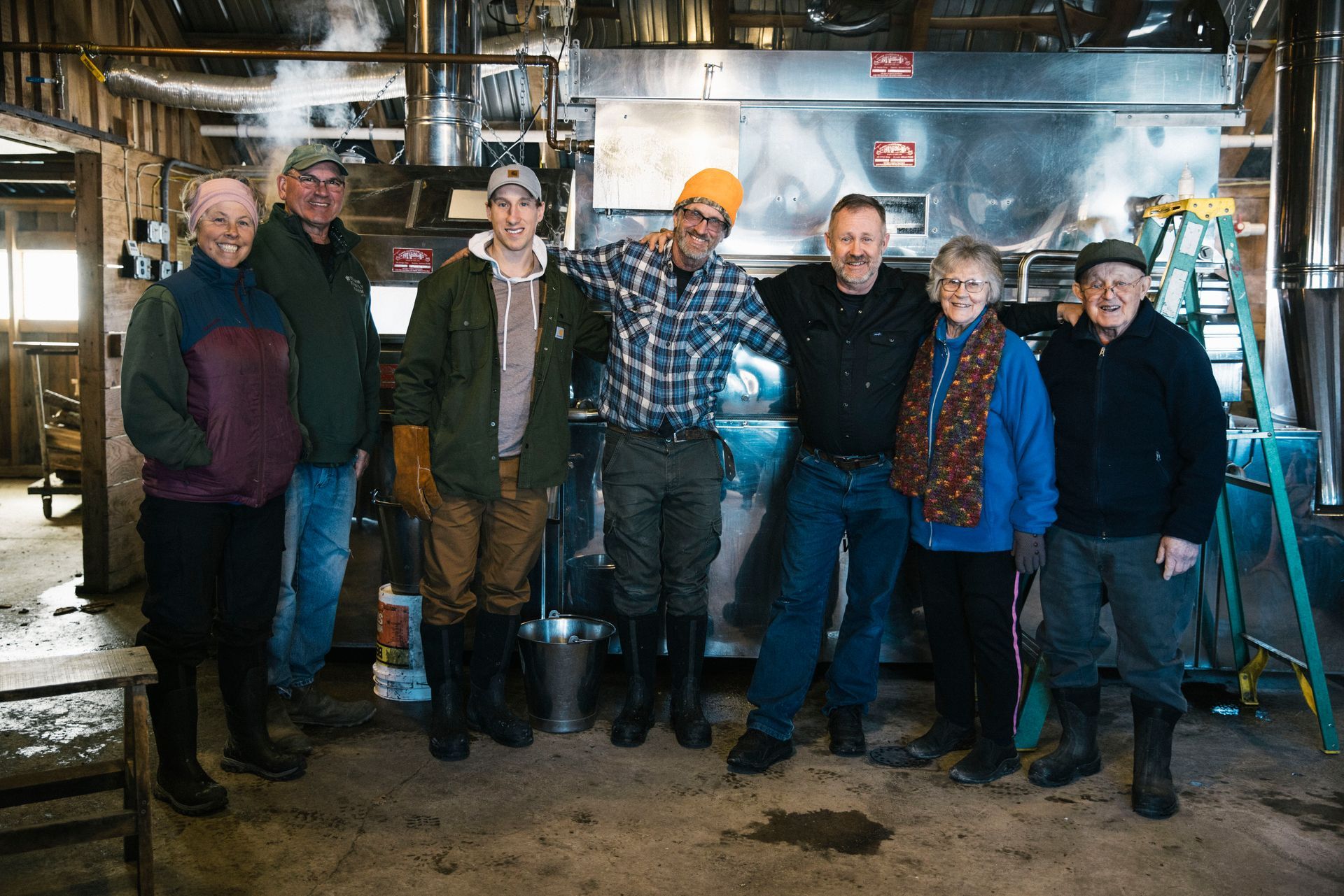 Isham family members standing in front of the maple production machinery at the farm